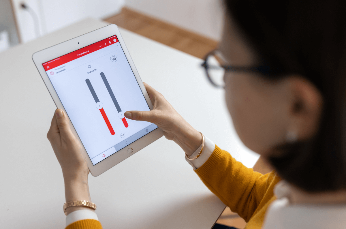 Kundin nutzt Tablet, um Einstellung ihres Hörgerätes zu ändern