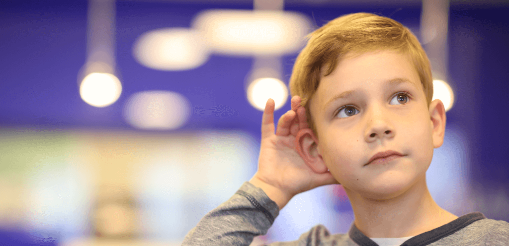 Kind hält hand hinter das ohr, um besser hören zu können